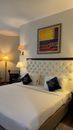 Luxurious hotel room featuring a plush bed, decorative pillows, and modern lighting for a cozy stay.