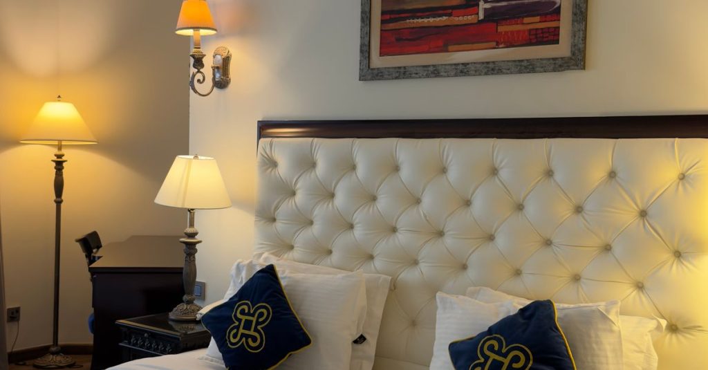 Luxurious hotel room featuring a plush bed, decorative pillows, and modern lighting for a cozy stay.